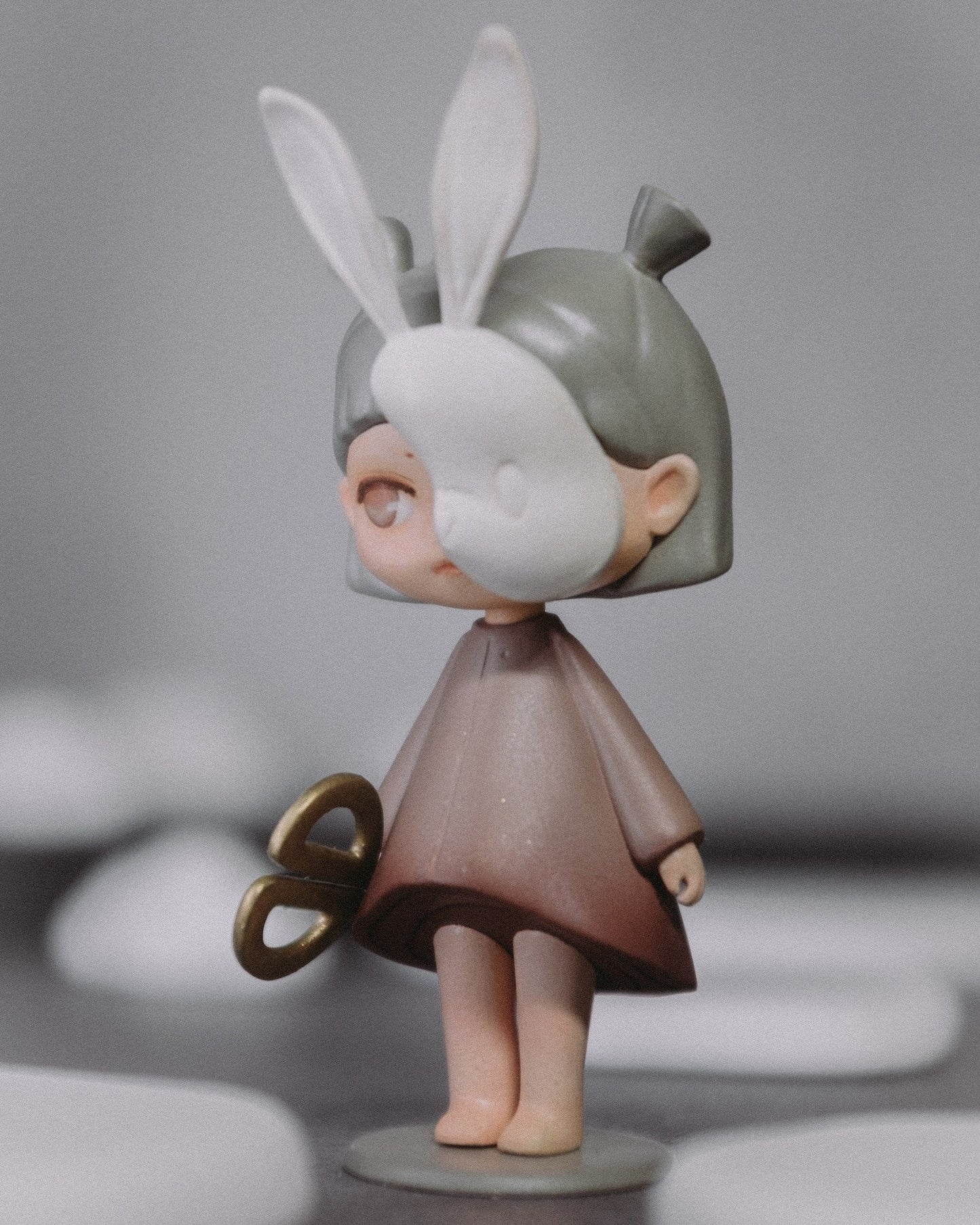 Side view of The Wanderer art toy, holding the gold scissors accessory.